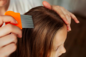 A una niña le están pasando la lendrera por el pelo